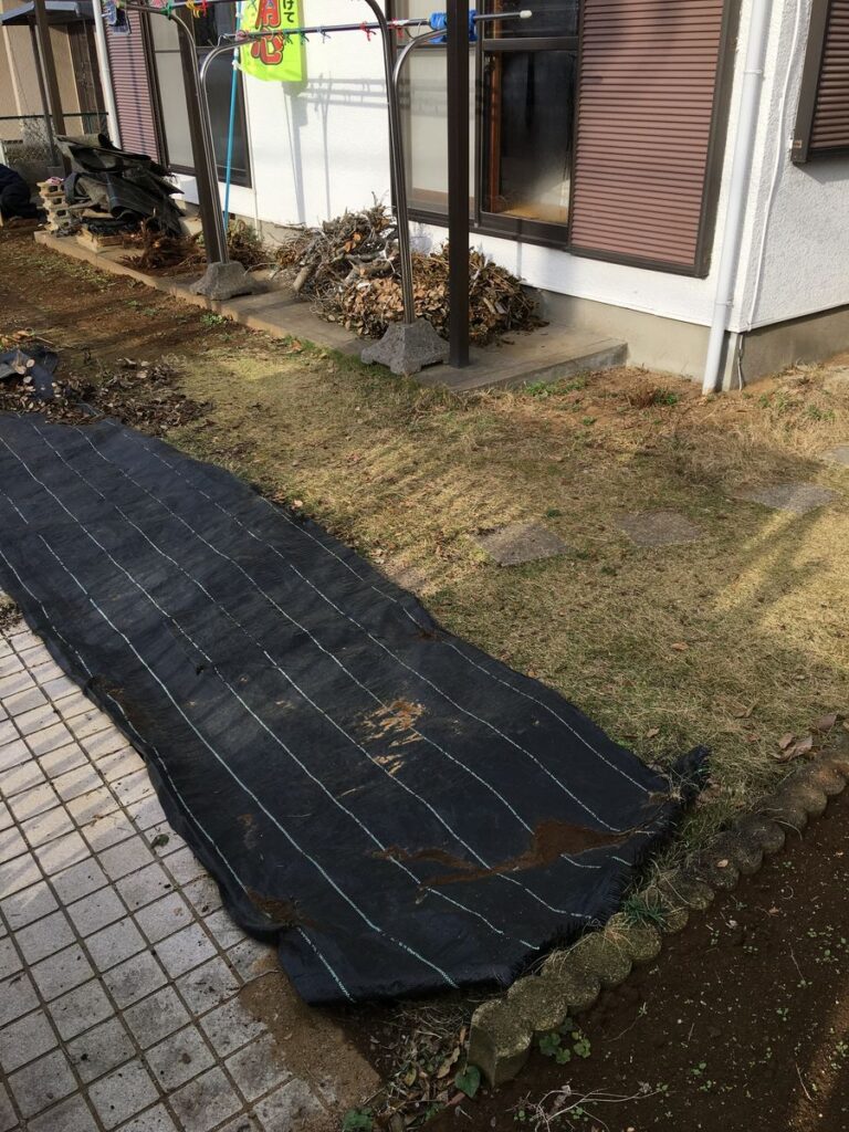 植え込みの脇に広げた防草シート